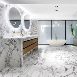 یک حمام با دیواره ها و کف از جنس سنگ مرمر طوسی با حطوط مشکی و یک وان سفید